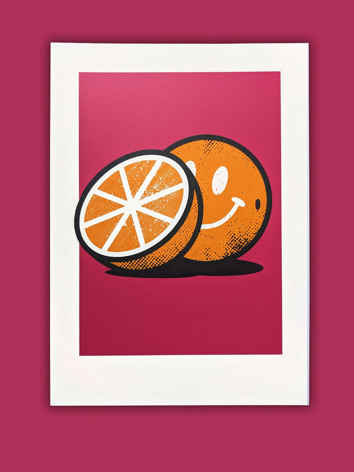 Big Love artwork by Gerard McDonagh, showing a whole orange with a smiling face and an orange half against a pink ground, shown on paper.